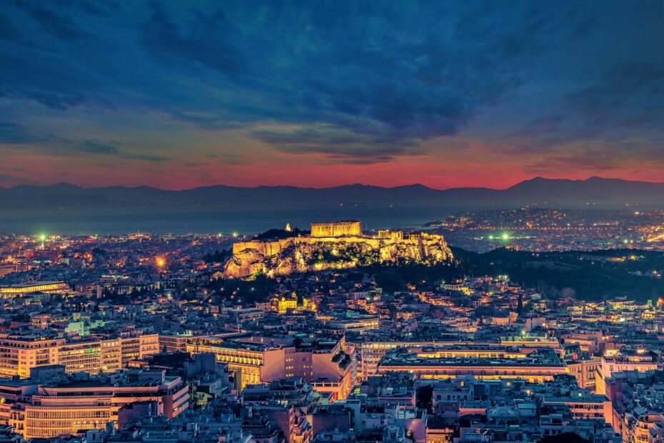 Stunning aerial shot of Athens cityscape with the illuminated Acropolis at twilight.