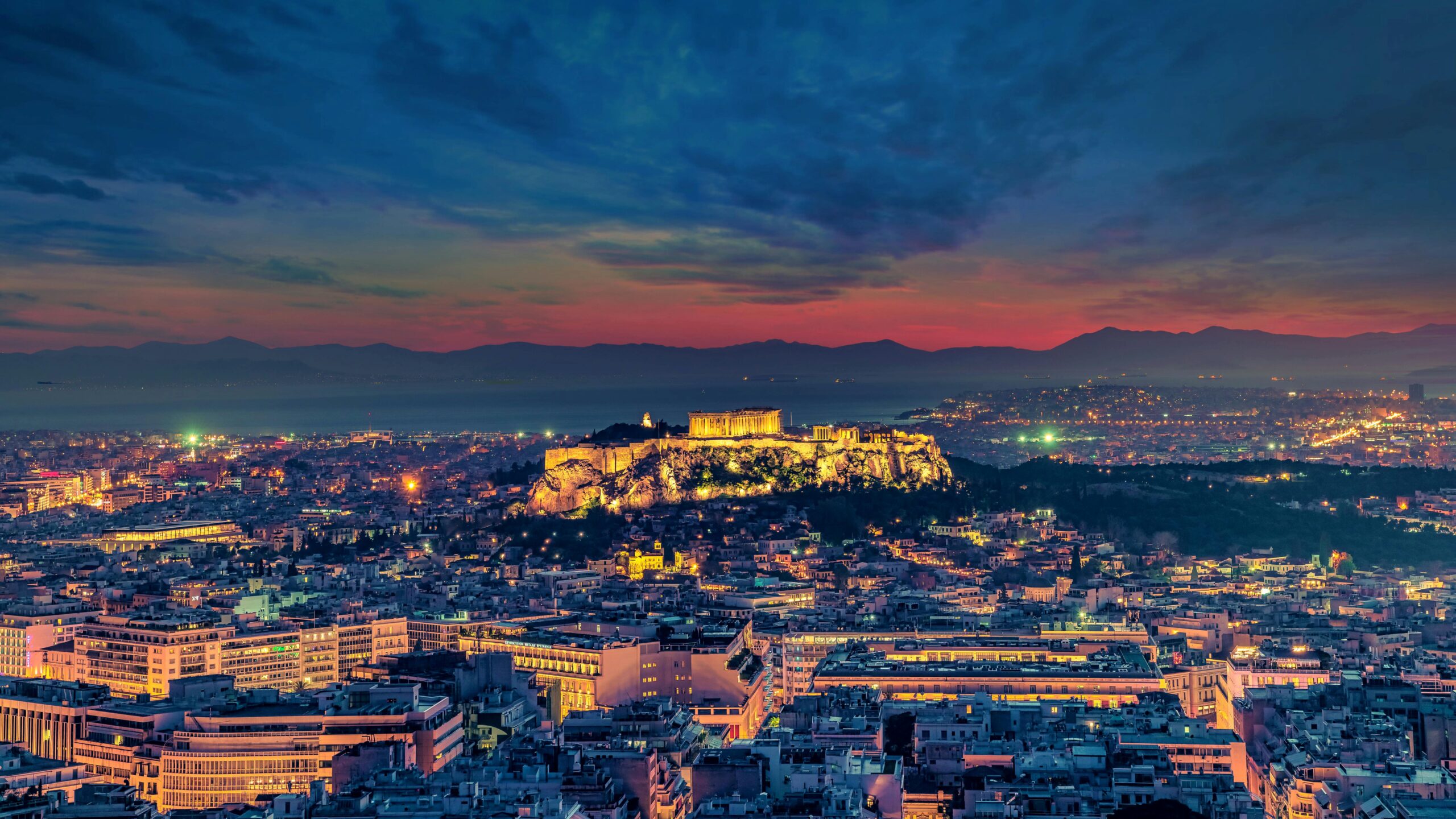 Stunning aerial shot of Athens cityscape with the illuminated Acropolis at twilight.